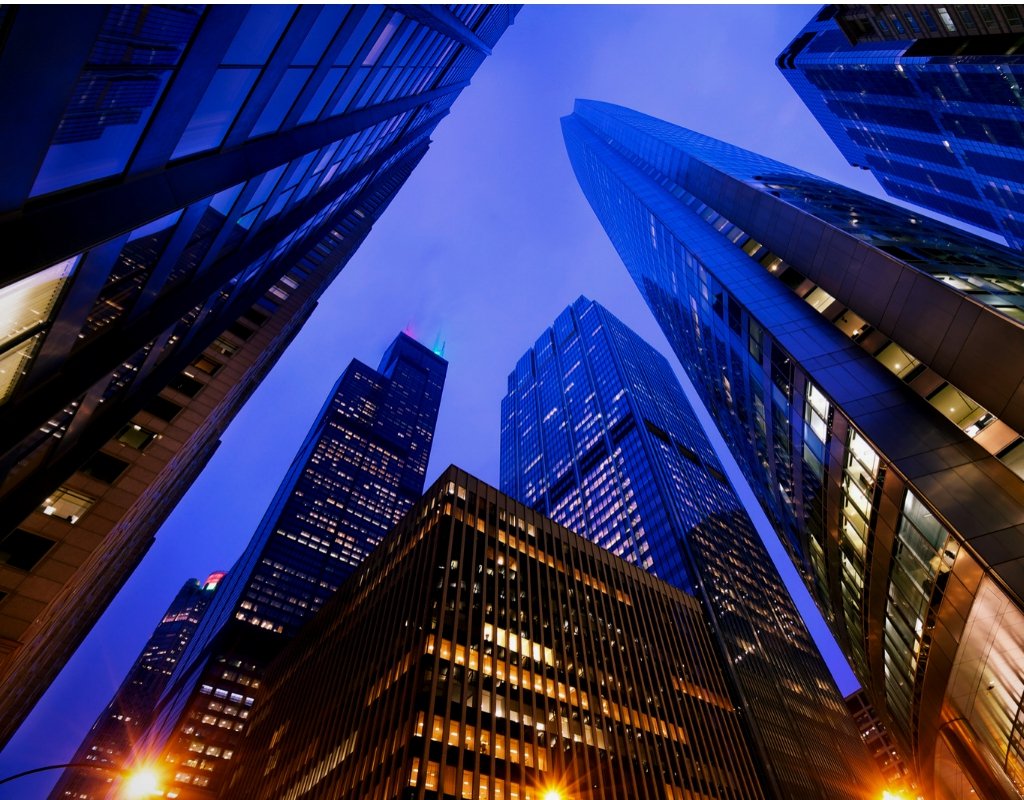 Skyscrapers reach into the night sky illuminated by street lights.