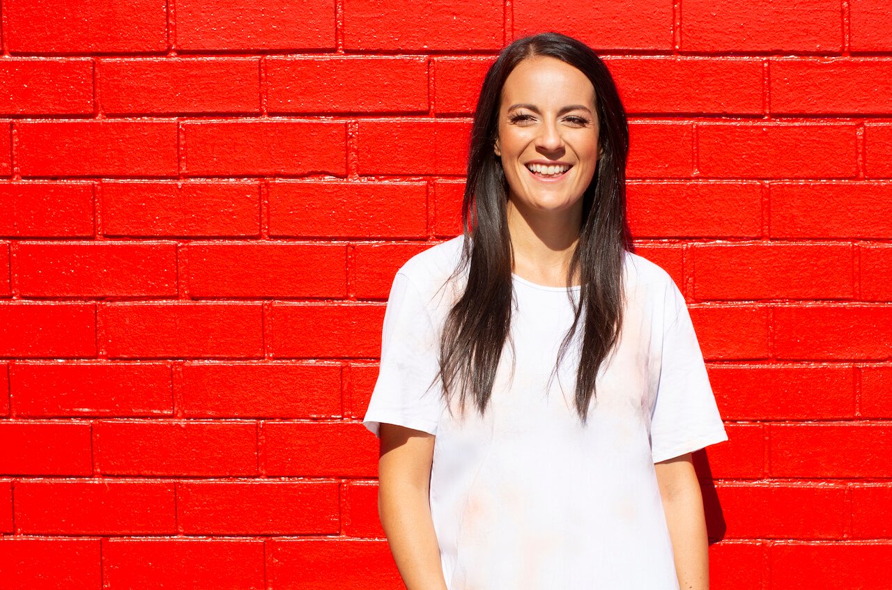 Teresa Truda standing infront of a red brick wall