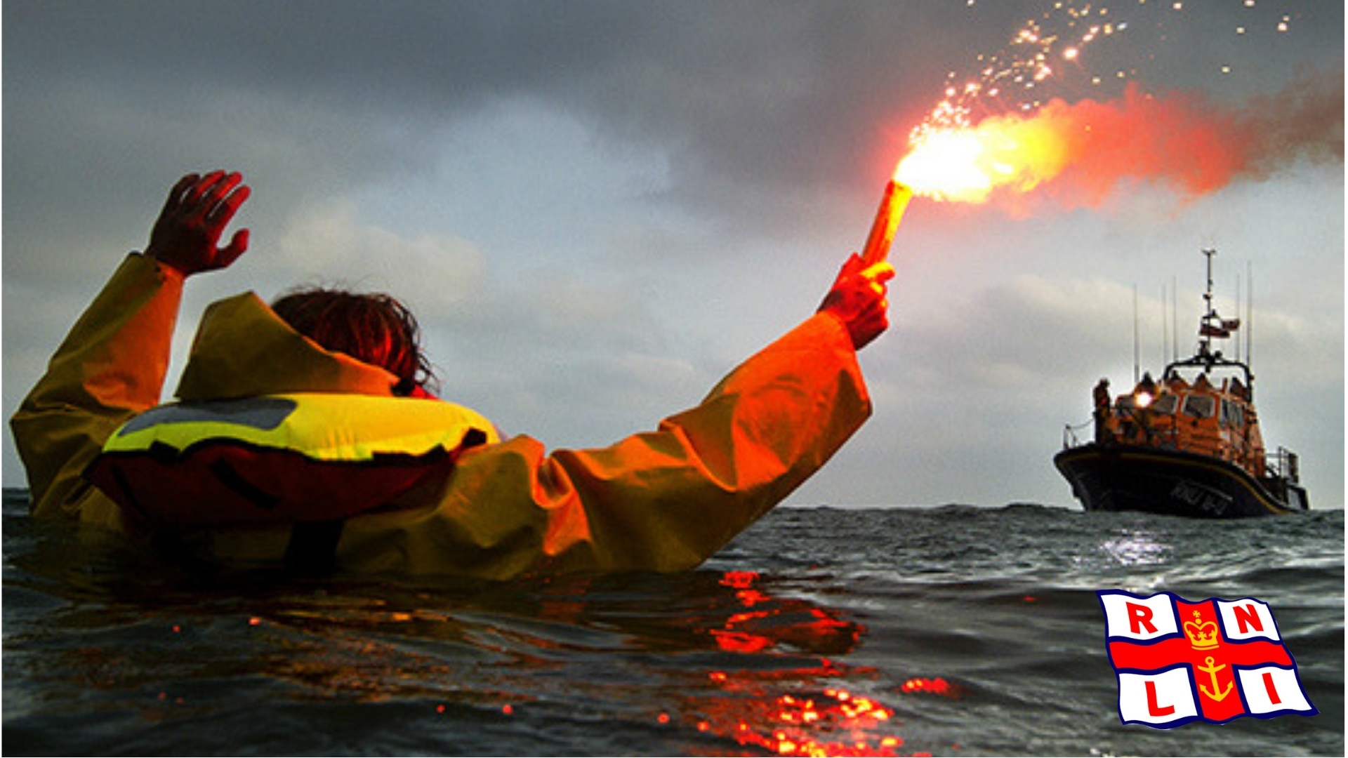 A castaway holding a signal rocket and an RNLI rescue ship in the distance.