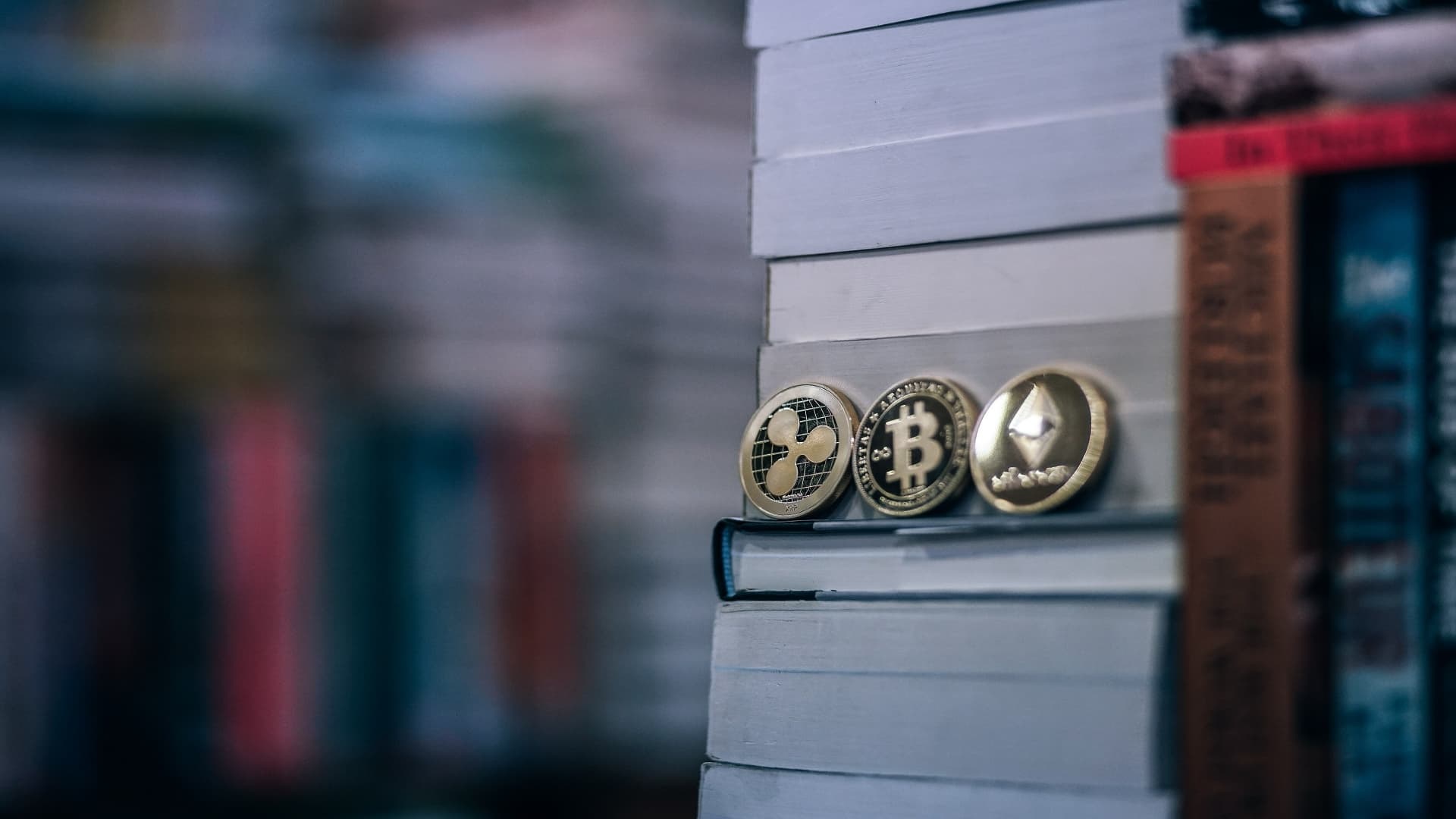 physical cryptocurrency coins with books in a library