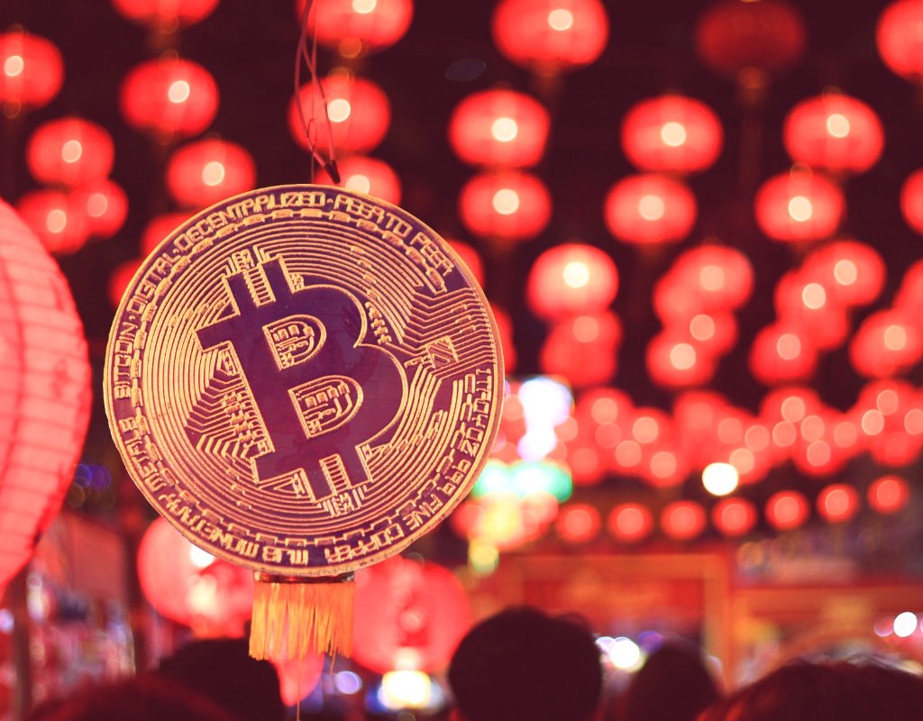 An artist rendering of a bitcoin superimposed over a photo of paper lanterns.