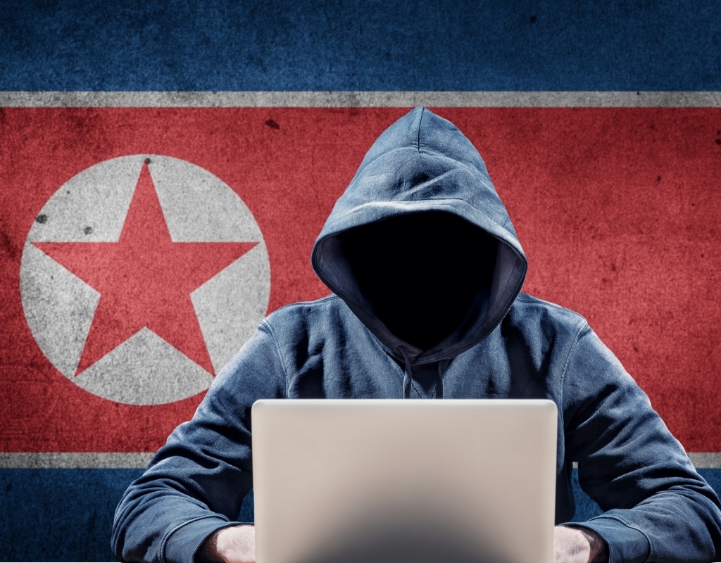 Computer hacker in front of North Korean flag.
