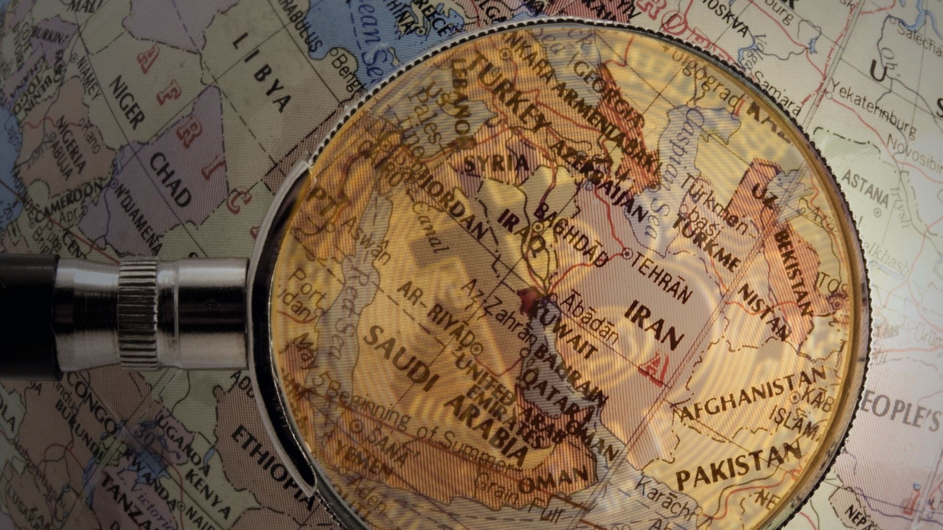 A magnifying glass hovers over a map of Central Asia.