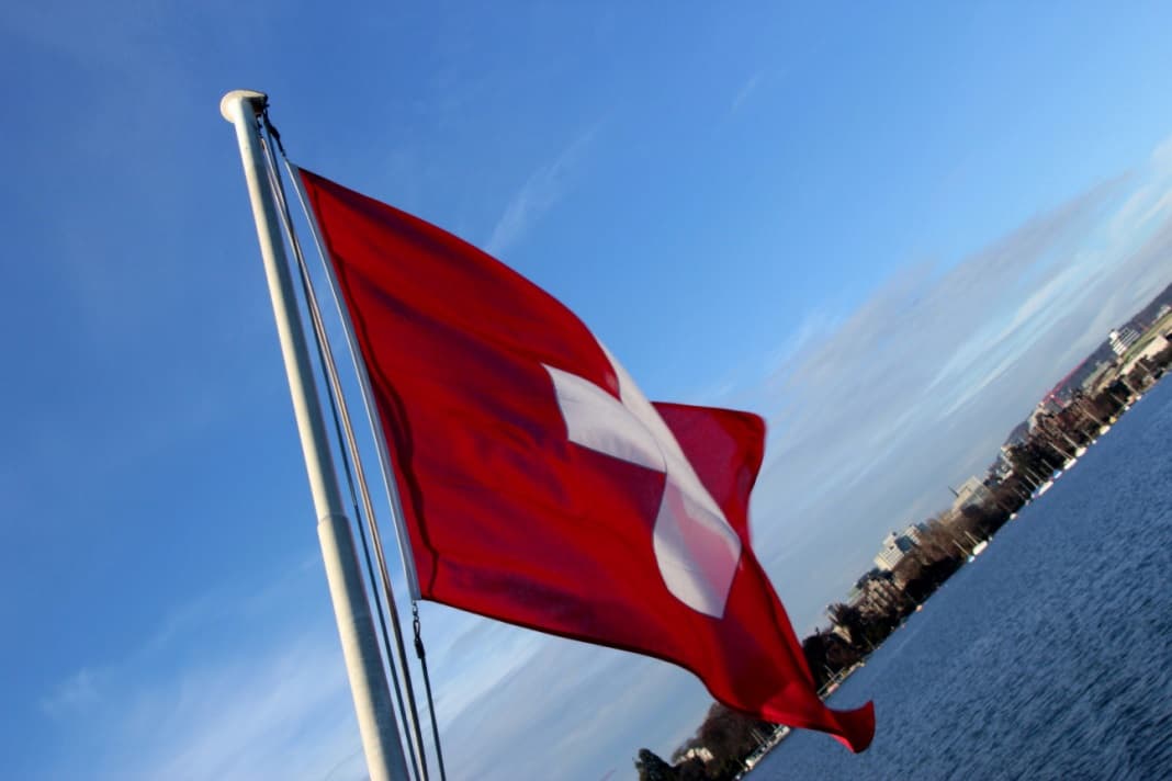 switzerland flag with city and lake in the background