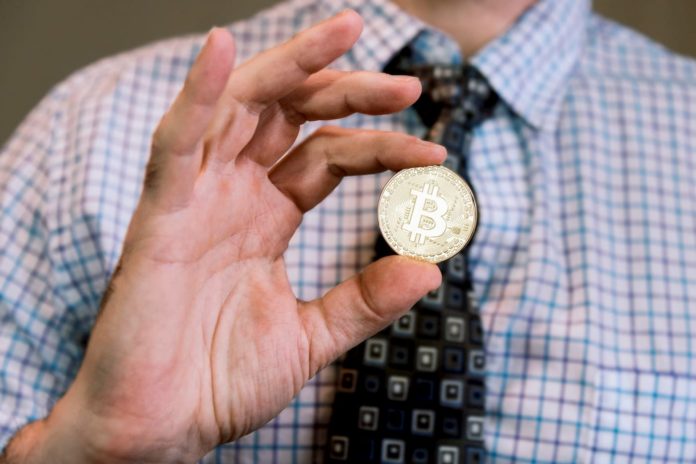 Businessman holding Bitcoin between fingers symbolising institutional investment in cryptocurrencies